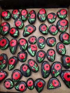 a box filled with black and red painted rocks covered in poppies on top of each other