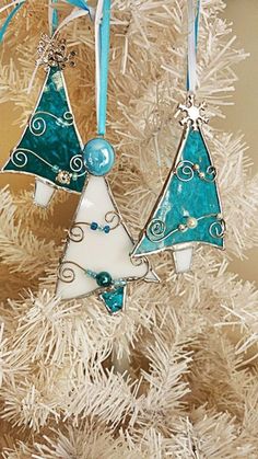 three ornaments hanging from a christmas tree on a white ornament with blue ribbon