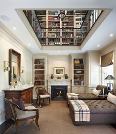 a living room filled with furniture and a fire place under a book shelf covered in books