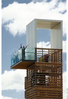 a man standing on top of a tall wooden structure with his arms in the air