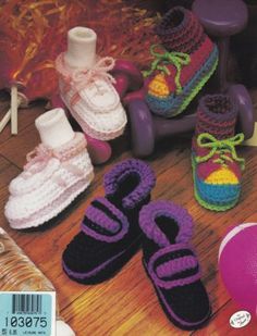 crocheted baby shoes and booties are on the floor next to a toy