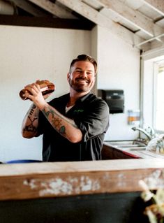 a man holding a doughnut in his right hand while standing next to a counter