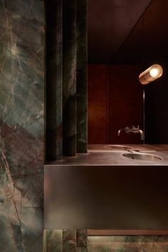 a bathroom sink sitting under a mirror next to a wall mounted faucet in a dark room