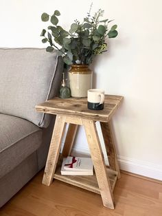 a wooden table sitting next to a couch with a plant on it and a mug