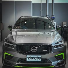 the front end of a car on display in a showroom with people looking at it