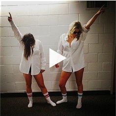 two women standing in front of a white wall with their arms up and legs crossed