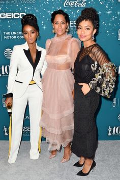 three women standing next to each other on a carpet