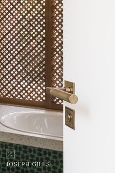 an open door to a bathroom with a bathtub in the corner and a wooden privacy screen behind it