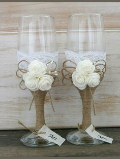 two wine glasses decorated with white flowers and twine