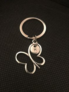 a metal keychain with a butterfly on it's side and the letter h in the middle