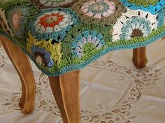 a crocheted foot stool sitting on top of a white tablecloth covered floor