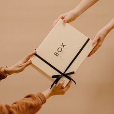 two women holding a box with the word boo on it and tied in black ribbon