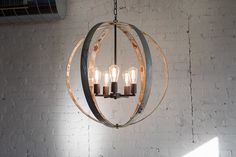 a chandelier hanging from a brick wall with candles in the middle and one light on each side