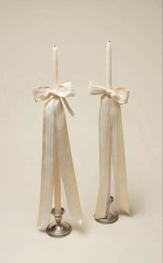 two candles with bows on them sitting next to each other