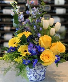 a blue and white vase filled with yellow flowers