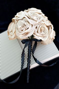 a bouquet of white roses sitting on top of a gift wrapped in black satin ribbon