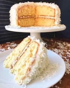 a slice of coconut cake on a plate with the rest of the cake in the background