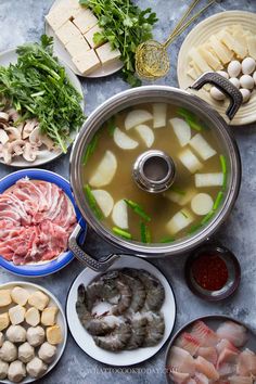 an assortment of food including meats, vegetables and soup is displayed on a table