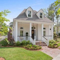 a white house with black shutters on the front porch and steps leading up to it