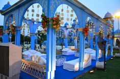 a blue and white gazebo with lots of pillows on it's sides in the evening