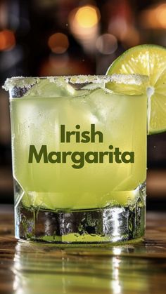 a glass filled with ice and lime sitting on top of a table