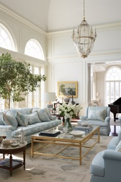 a living room filled with furniture and a chandelier hanging from the ceiling next to a piano