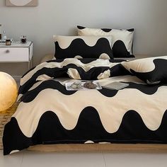 a bed with black and white comforters on top of it next to a night stand