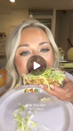 a woman is eating a sandwich with lettuce on it