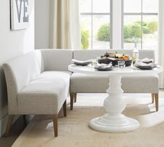 a white table with two chairs and plates on it in front of a large window