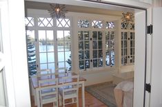 an open door leading to a dining room with table and chairs in front of the window