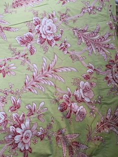 a green and pink floral print fabric with white flowers on the bottom half of it