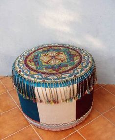 a colorful ottoman sitting on top of a tile floor next to a wall and window