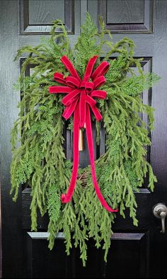 a wreath with a red bow hanging on the front door