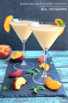 two glasses filled with peaches and cream martini on top of a slate tray next to sliced peaches