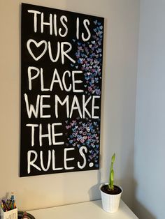 a sign that says this is our place we make the rules next to a potted plant