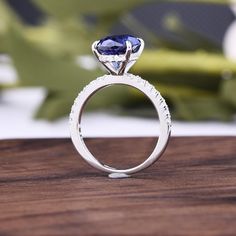 a close up view of a ring with a blue stone in the center on a wooden surface