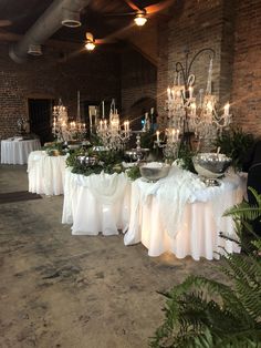 a banquet table with white linens and greenery is set up for an event