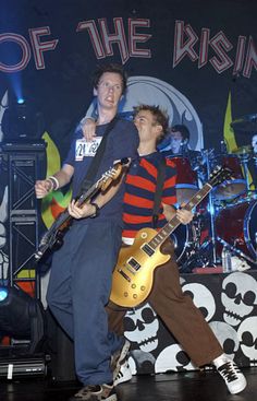 two young men are playing guitar on stage