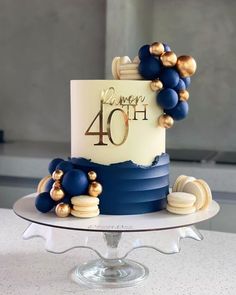 a blue and white cake with gold decorations on it's top is sitting on a table