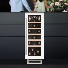 a man and woman standing next to each other near a wine cooler