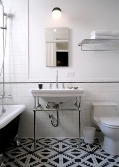 a black and white tiled bathroom with a claw foot bathtub, sink, toilet and mirror