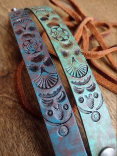 two metal bracelets sitting on top of a wooden table