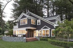 a house that is in the middle of some trees and grass with bushes around it