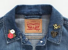 a denim jacket with two different patches on it and a heart shaped pin in the back