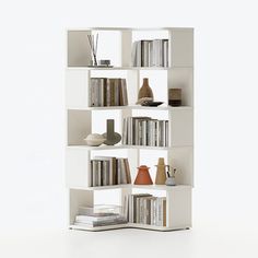 a white book shelf filled with books and vases on top of eachother