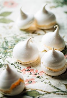 small white desserts are sitting on a floral tablecloth