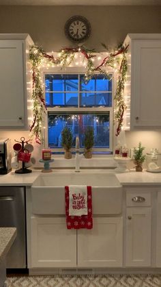 a kitchen decorated for christmas with lights and garland on the window sill above the sink