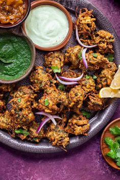 an assortment of food on a platter with sauces and herbs next to it