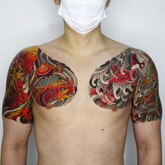 a man with tattoos on his chest wearing a face mask