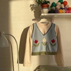 a knitted sweater hanging on a wall next to a lamp and potted plant